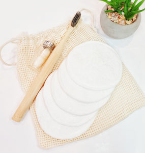 Reusable makeup remover pads, bamboo toothbrush and biodegradable corn floss in glass bottle