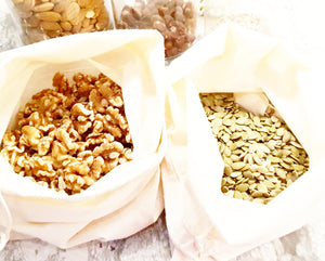 Two reusable bulk bags containing walnuts and pumpkin seeds