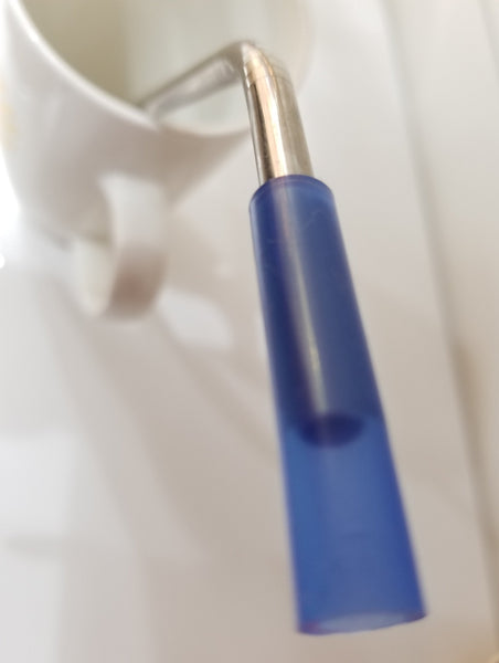 Closeup blue silicone tip on reusable stainless steel straw in mug.
