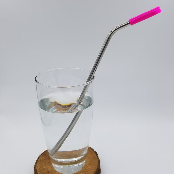 Pink silicone tip on bent stainless steel straw in glass with water.
