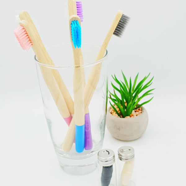 Bamboo toothbrushes in glass with bamboo and corn floss in containers.