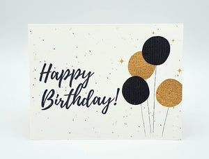 Plantable seed card with "Happy Birthday" in cursive with gold and black balloons.