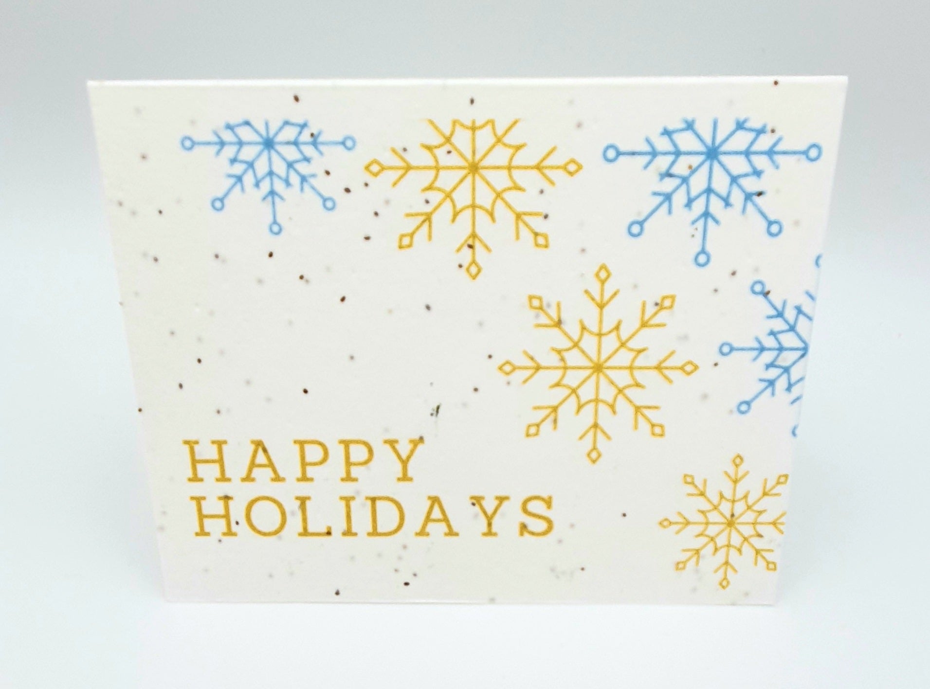 Plantable seed paper Happy Holidays with gold and blue snowflakes.