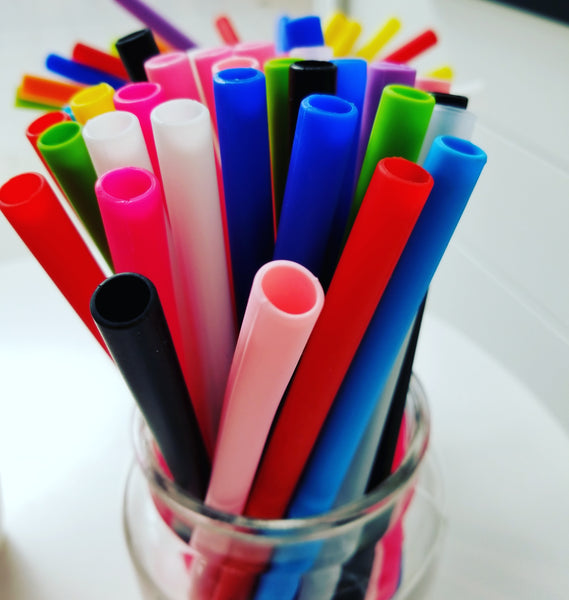 Various colours reusable silicone straight straws in glass.